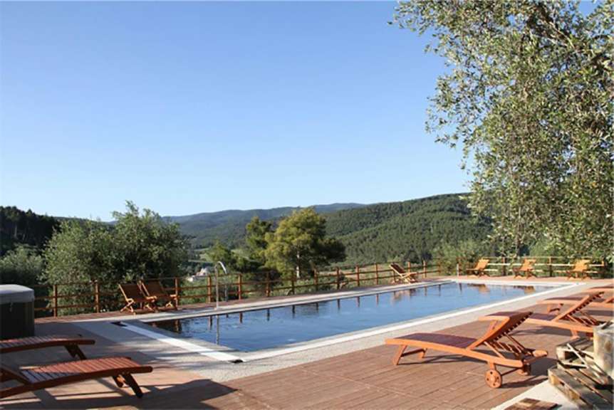 Liegestühle stehen um einen Pool mit Blick auf die Berge