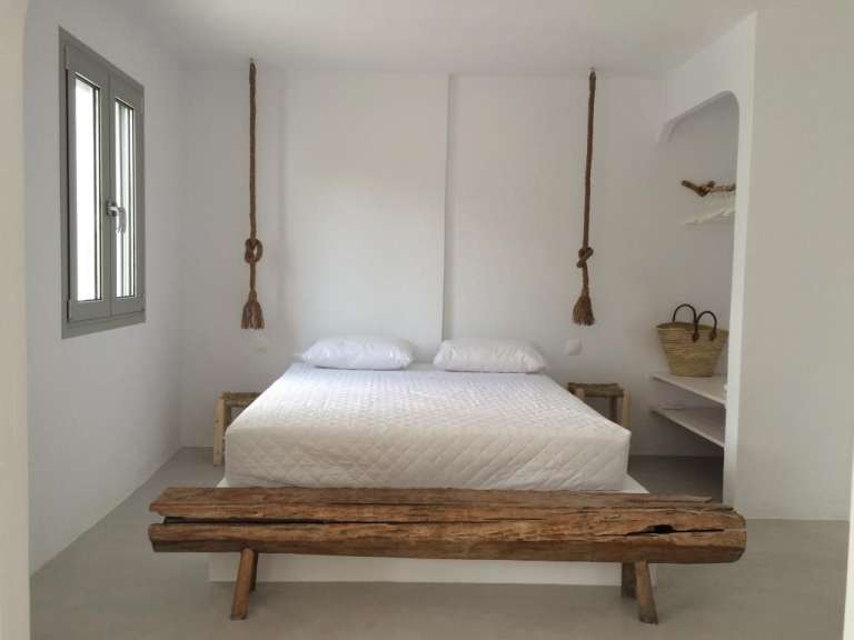 Ein weißes Schlafzimmer mit einem Bett und einer Holzbank