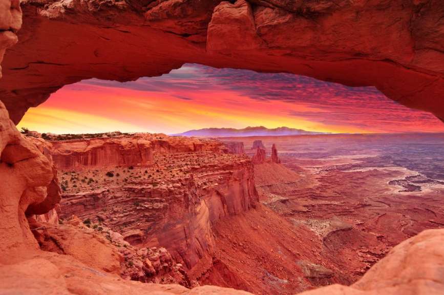 Ein Sonnenuntergang in der Wüste wird durch eine Felsformation gesehen