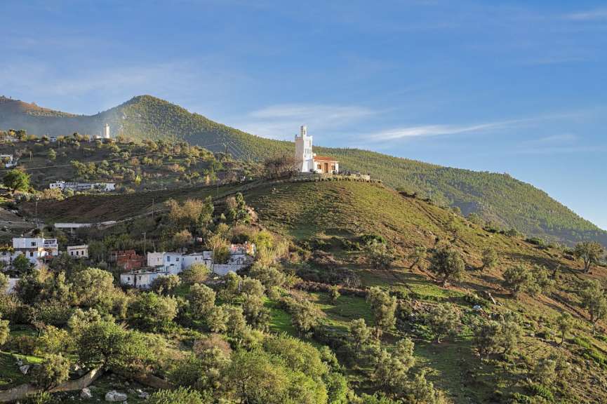 Ein weißes Gebäude sitzt auf einem Hügel inmitten einer grünen Landschaft