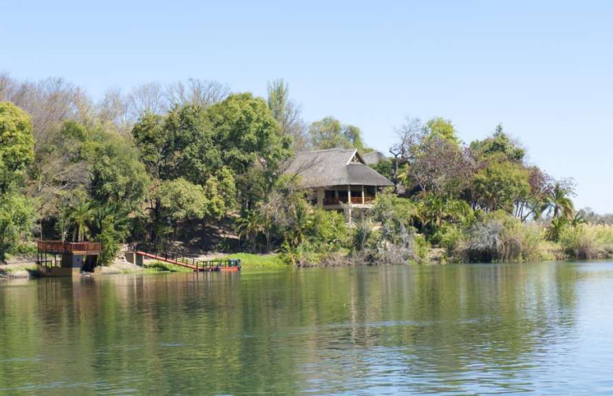 Ein Haus mit Strohdach sitzt auf einer kleinen Insel am Ufer eines Flusses