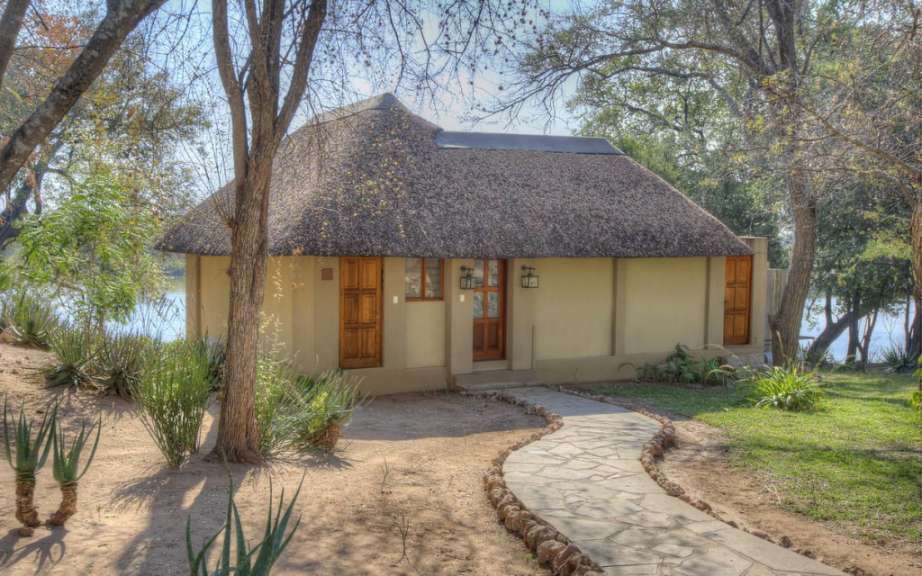 Ein Haus mit Strohdach steht neben einem Fluss