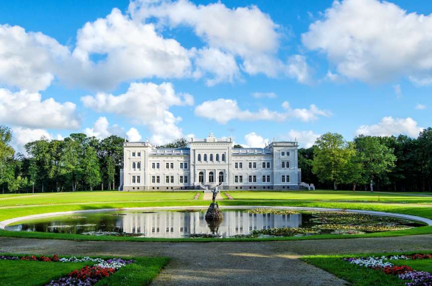 Ein großes weißes Gebäude mit einem Brunnen davor