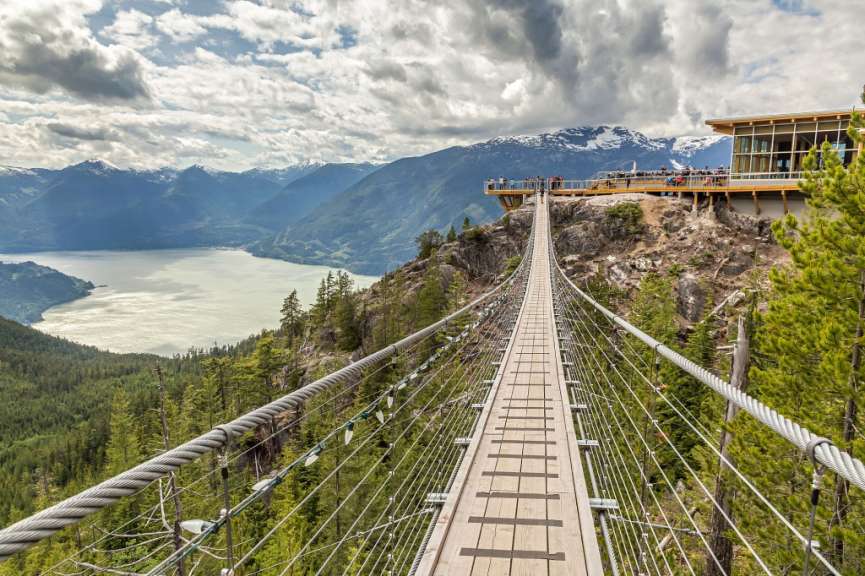 Eine Hängebrücke über einen See mit Bergen im Hintergrund