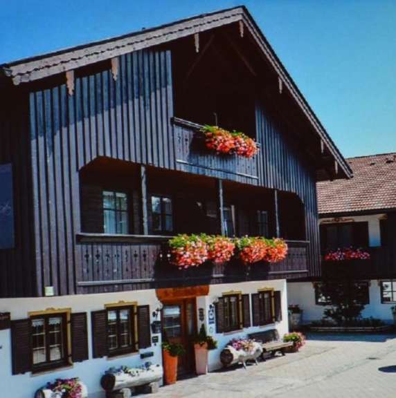 Ein braunes Haus mit einem Balkon und Blumen darauf