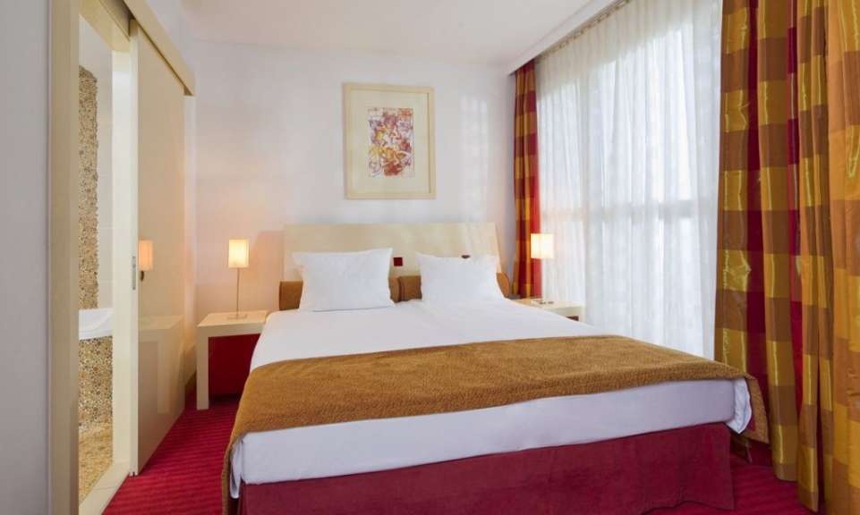 Ein Hotelzimmer mit einem Doppelbett, zwei Nachttischen, einer Lampe und einem Gemälde an der Wand.