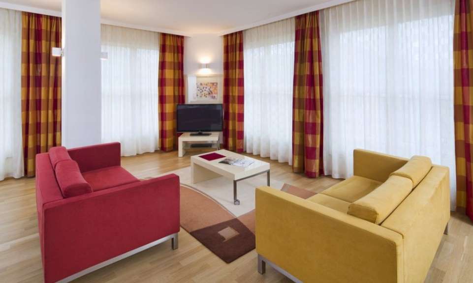 Ein Wohnzimmer mit zwei Sofas, einem Couchtisch, einem Fernseher und karierten Vorhängen.