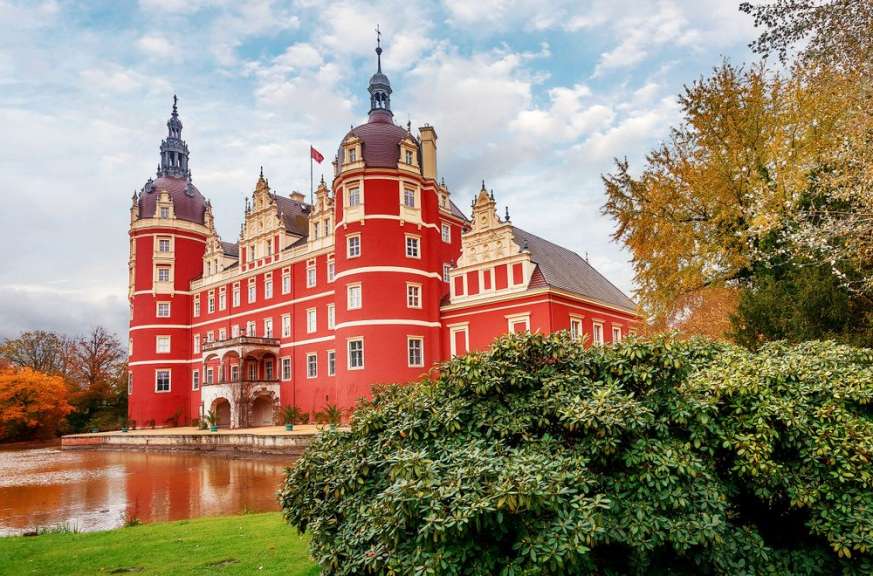 Ein großes rotes Schloss mit einem See im Vordergrund