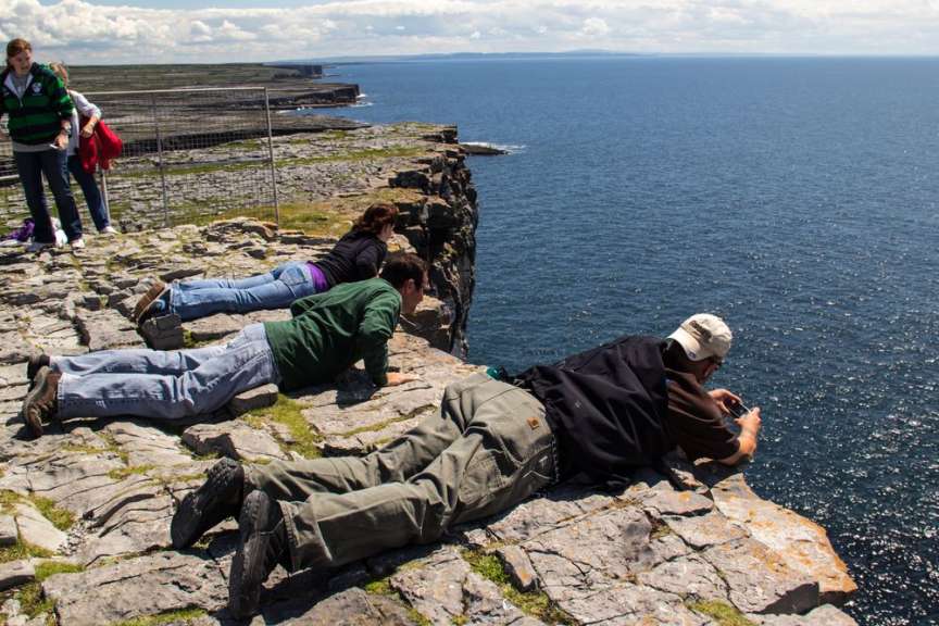 Eine Gruppe von Menschen liegt auf einer Klippe mit Blick auf das Meer