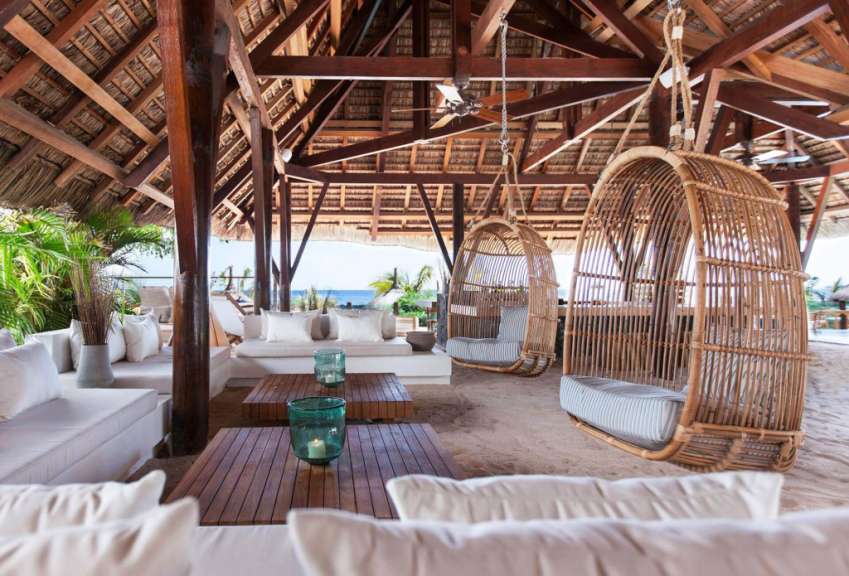 Ein Wohnzimmer mit weißen Möbeln und hängenden Stühlen