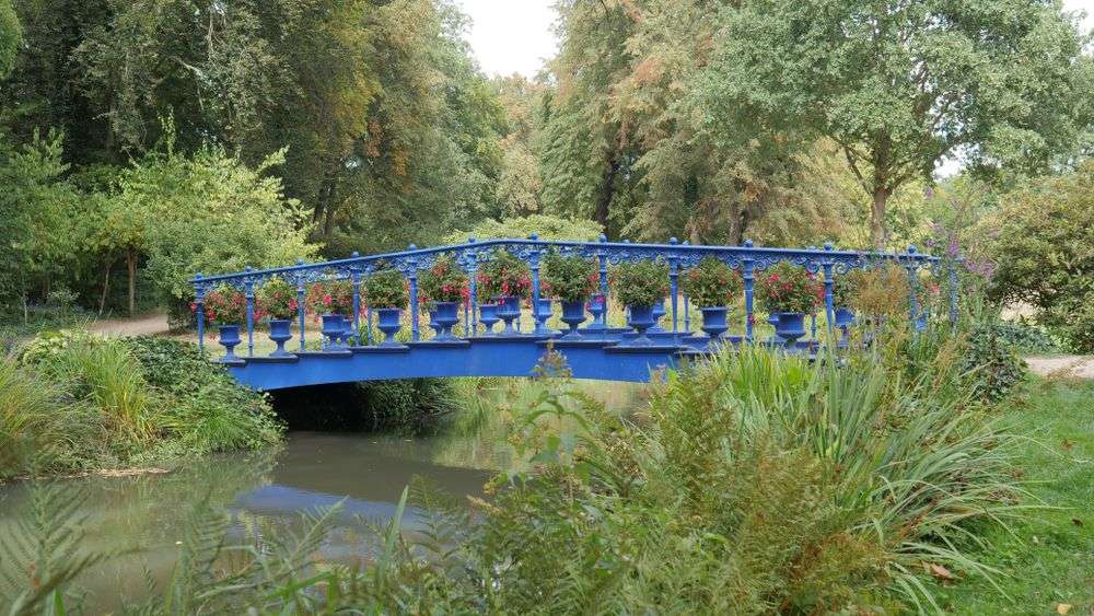 Eine blaue Brücke über einen Fluss im Park
