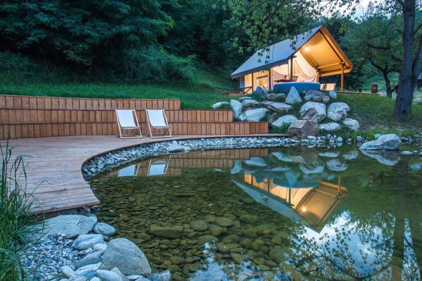 Ein Zelt sitzt auf einem Hügel neben einem Teich