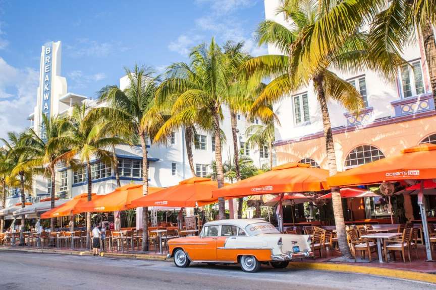 Ein orangefarbenes Auto steht vor einem Restaurant mit orangefarbenen Sonnenschirmen