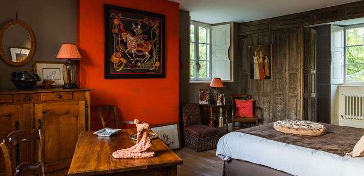 Ein Schlafzimmer mit einem großen Gemälde an der orangefarbenen Wand