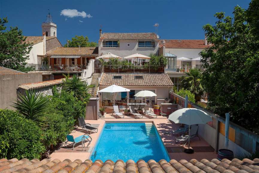 Ein großer Pool mit Liegestühlen und Sonnenschirmen in der Nähe eines Hauses