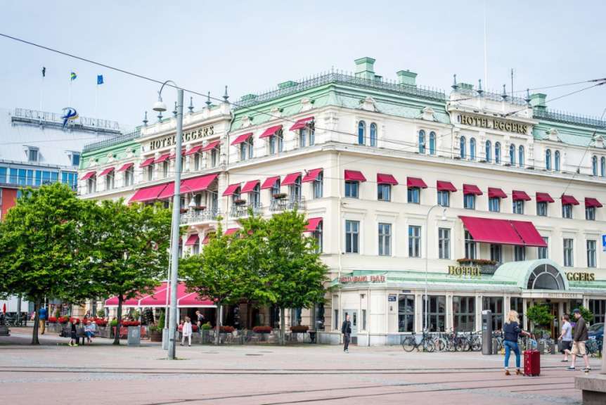 Eine Frau geht vor einem großen Hotel mit roten Vorhängen