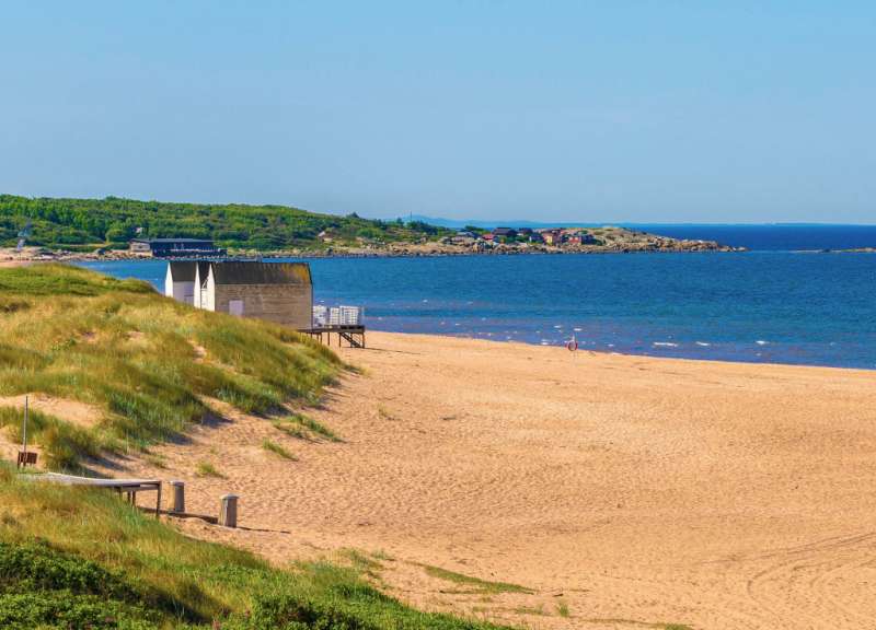 Ein Strand mit einem kleinen Gebäude in der Ferne