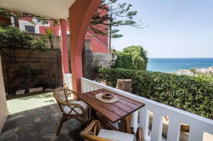 Ein Tisch und ein Stuhl auf einem Balkon mit Blick auf das Meer
