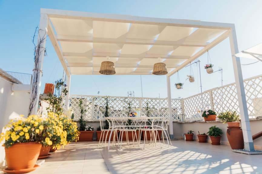 Ein weißer Tisch und Stühle unter einer weißen Pergola
