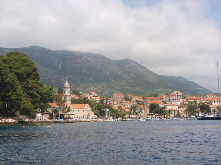 Ein kleines Dorf liegt am Ufer eines Sees mit Bergen im Hintergrund