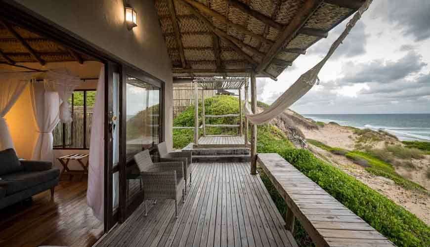 Ein Holzdeck mit einer Hängematte darauf und einem Blick auf den Ozean .