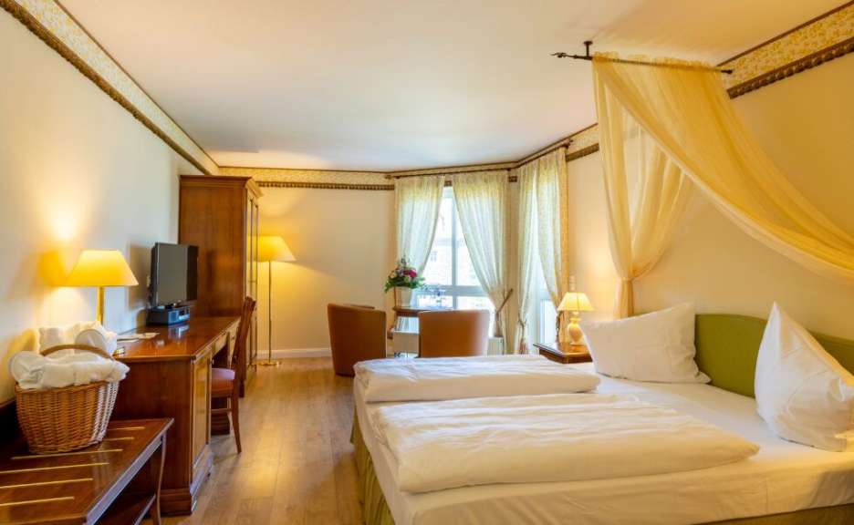 Ein Hotelzimmer mit einem großen Bett und einem Schreibtisch ist zu sehen.