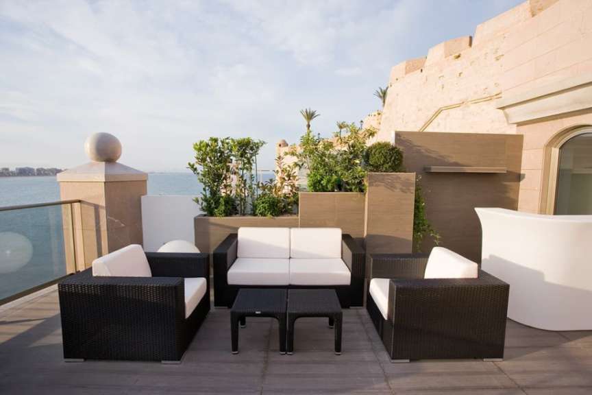 Eine Terrasse mit Möbeln und einem Tisch mit Blick auf das Meer