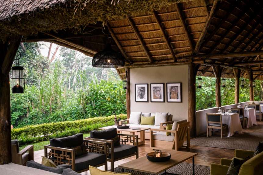 Eine überdachte Terrasse mit tropischer Vegetation, Sitzmöbeln und gedeckten Tischen.
