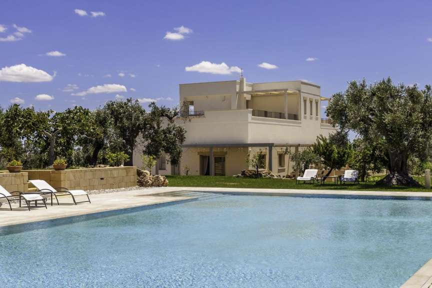 Ein großes weißes Haus mit einem Pool im Vordergrund