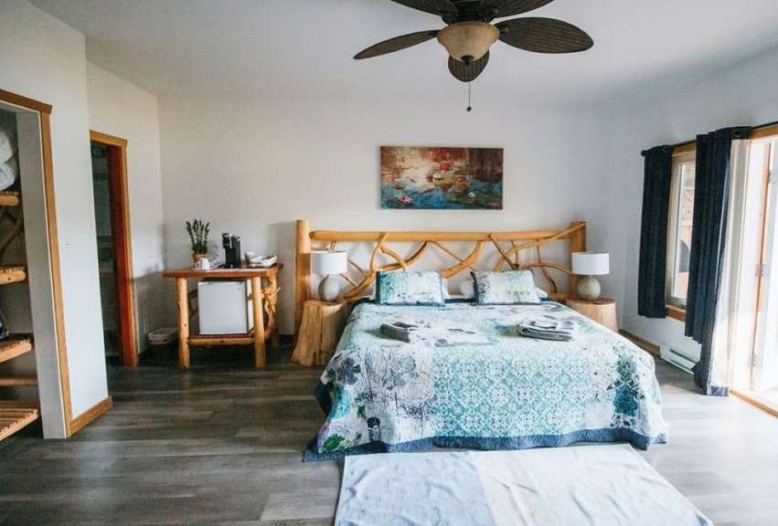 Ein Schlafzimmer mit einem rustikalen Holzbett, einem Nachttisch mit Minibar und einem Wandbild.