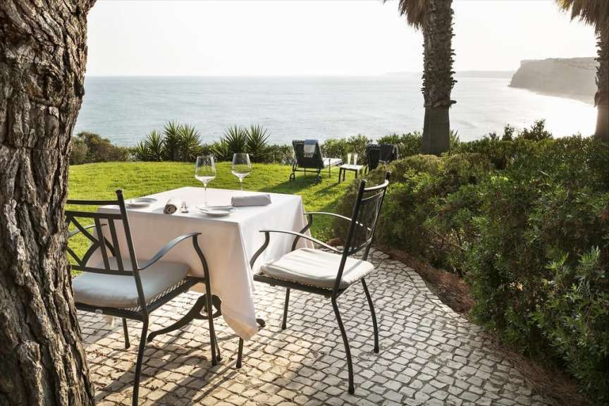 Ein Tisch und Stühle stehen auf einer Terrasse mit Blick auf das Meer