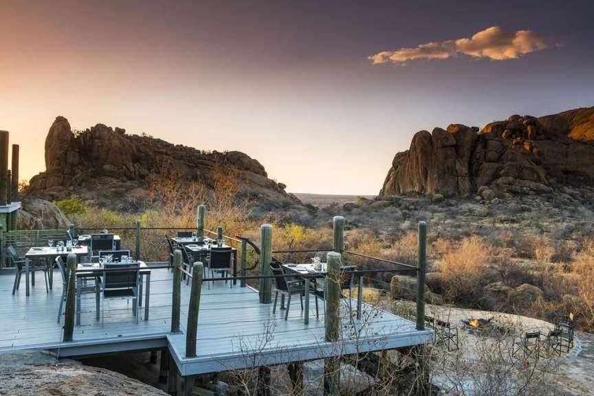 Eine Terrasse mit Tischen und Stühlen mit einem Berg im Hintergrund