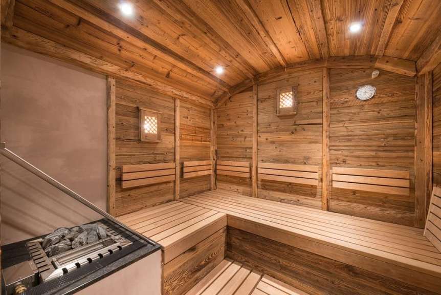 Die rustikale Holzsauna verfügt über mehrere Sitzbänke und einen Ofen mit heißen Steinen.