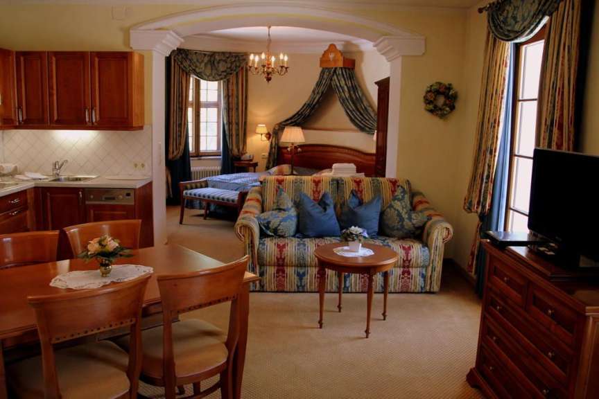 Ein Suite-Zimmer mit einem Essbereich, einem Wohnzimmer mit Sofa und einem Schlafbereich ist sichtbar.
