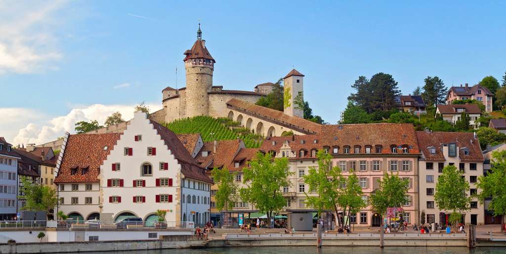 Eine Reihe von Gebäuden neben einem Fluss mit einem Turm darauf