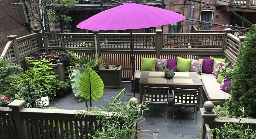 Eine Terrasse mit einem Tisch und Stühlen und einem lila Regenschirm