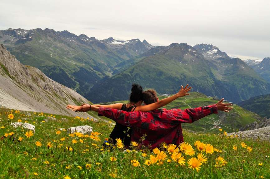 Ein Mann und eine Frau sitzen auf einer Wiese mit Blick auf die Berge