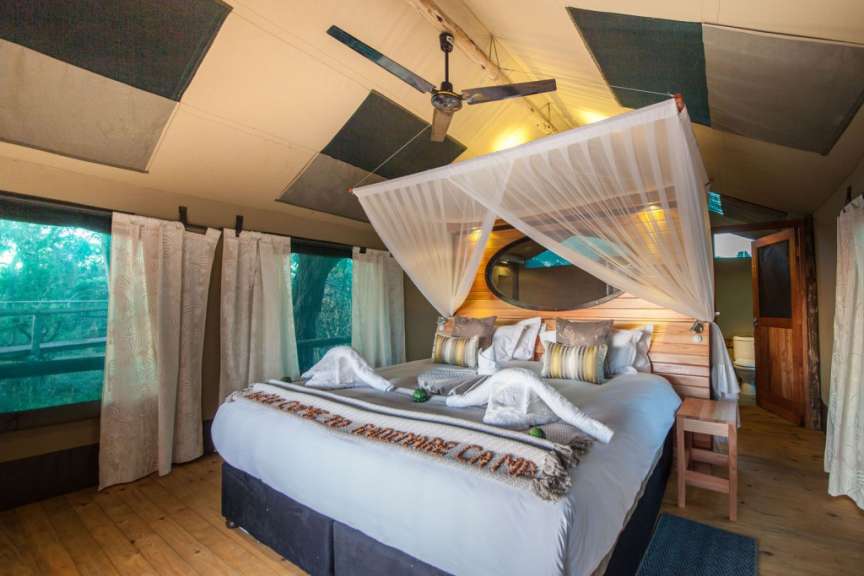 Ein Bett in einem Zelt mit der Aufschrift „ welcome to bartrade camp “ darauf