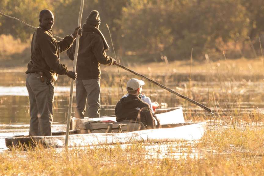 Zwei Männer rudern ein weißes Kanu auf einem Fluss