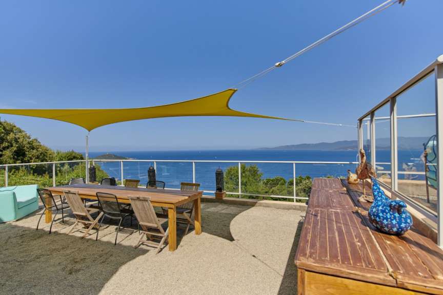 Ein Tisch und Stühle auf einer Terrasse mit Blick auf das Meer