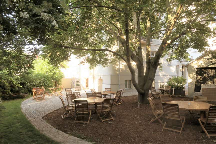 Tische und Stühle in einem Garten mit einem Baum im Hintergrund