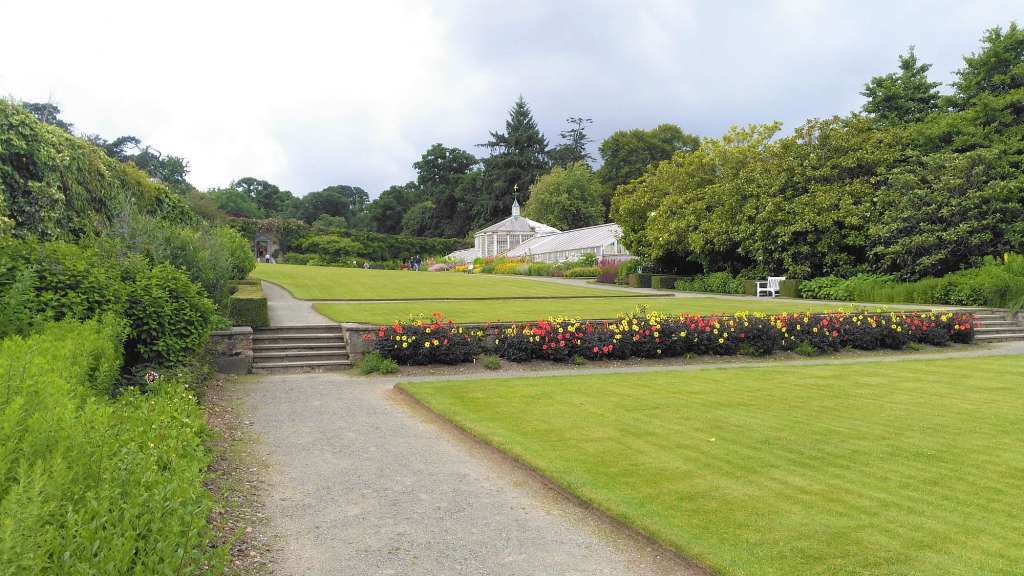 Ein Garten mit einem großen Gewächshaus im Hintergrund