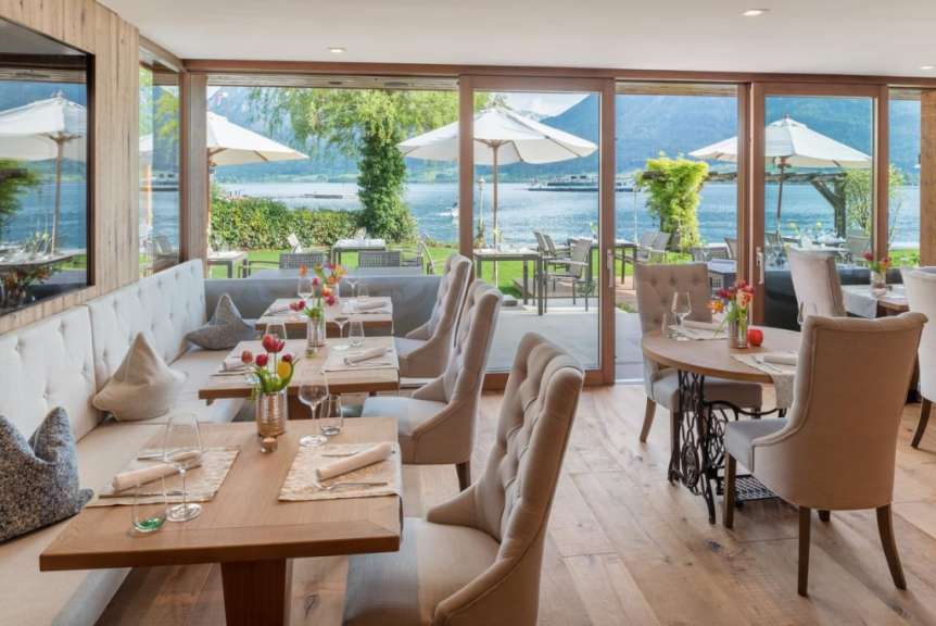 Ein Restaurant mit Blick auf einen See mit vielen Tischen und Stühlen