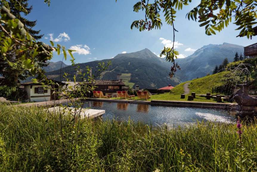 Ein malerischer Poolbereich mit Liegestühlen und Bergblick in einem Bergdorf.