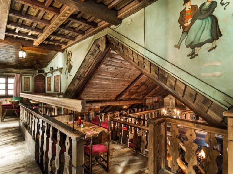 Ein rustikales Interieur eines Holzhauses, das mit traditionellen Malereien und Möbeln eingerichtet ist.