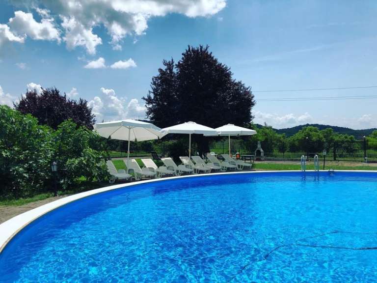 Ein großer Swimmingpool mit weißen Stühlen und Regenschirmen umgeben
