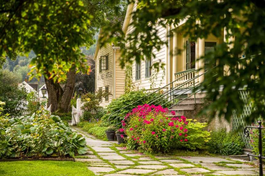 Ein gelbes Haus mit einer Treppe und rosa Blumen