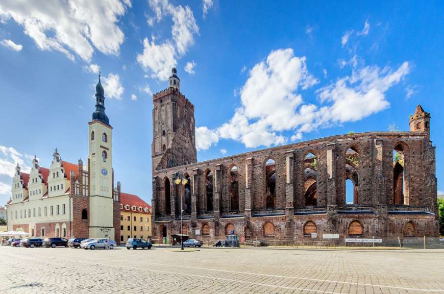 Ein großes Gebäude mit einem Uhrturm steht neben einem ruinierten Gebäude