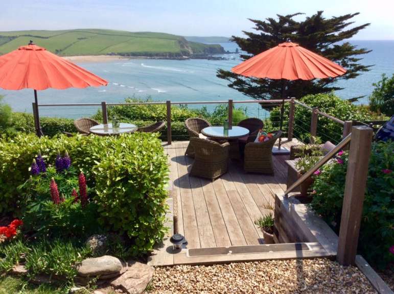Eine möblierte Terrasse mit Blick auf einen Strand und das Meer.