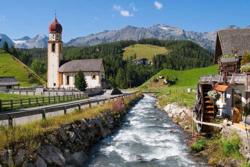 Ein Fluss fließt durch ein Dorf mit einer Kirche im Hintergrund